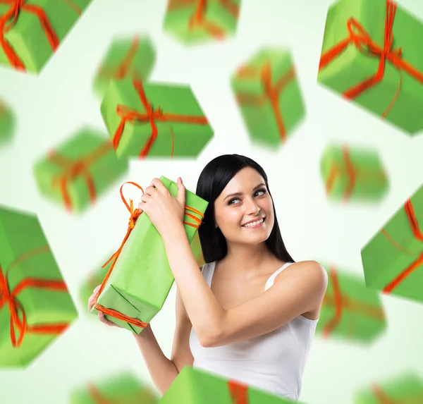 A portrait of dreaming woman who imagines green gift boxes. Light green background.