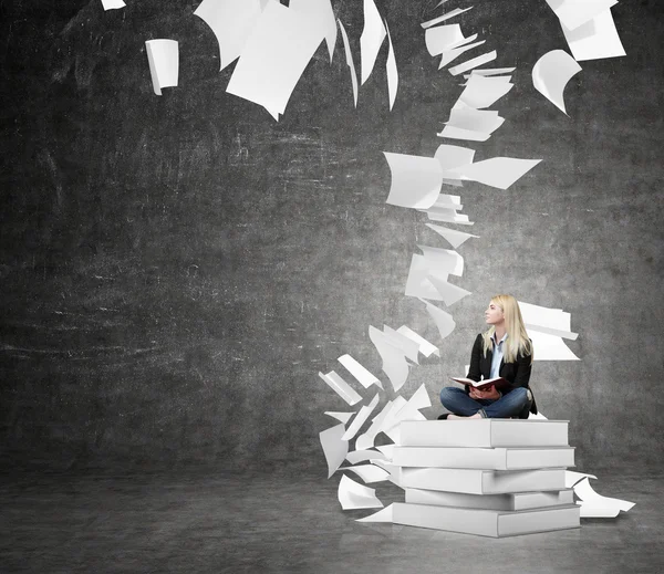 Woman sitting on a pile of books thinking about problem