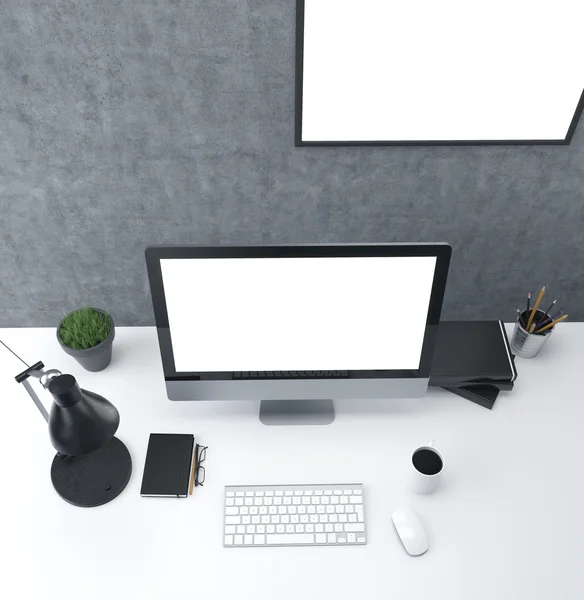 Workplace: a computer with blank screen, lamp, plant, organizer and glasses, cup, mouse, three datebooks and  pencils; white blank frame on the wall. Top view. Concept of work.