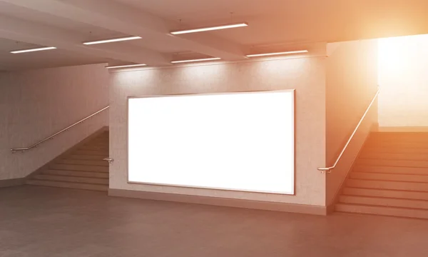 A big blank horizontal billboard in the underground, stairs up on both sides.