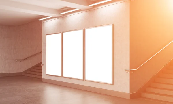 Three blank vertical billboard in the underground crossing, stairs up on both sides, blue sky seen from the street.