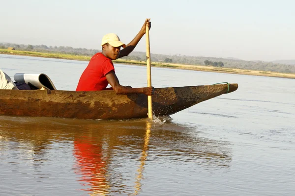 Young Malagasy african boy rowing traditional canoe on river