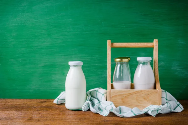 Milk bottles in the box on green background.