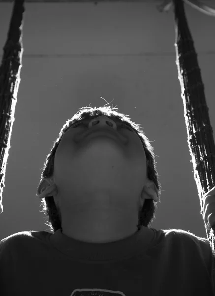 Little boy playing swing indoor rim light black and white