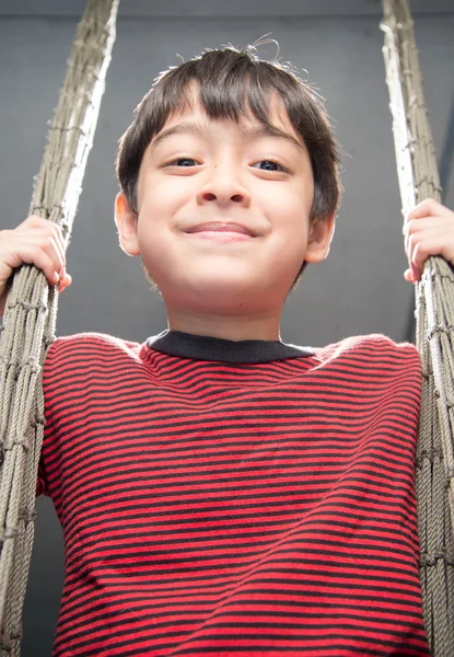 Little boy playing swing indoor rim light black and white