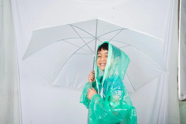 Little boy wearing rain coat on white background