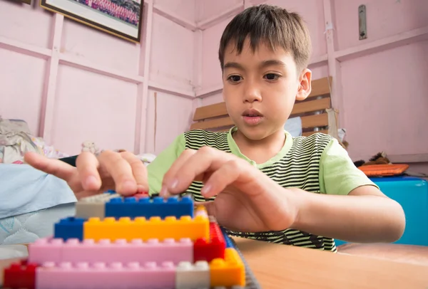 Little boy playing plastic block building indoor activity education