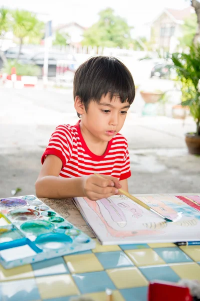 Little boy drawing picture on table outdoor