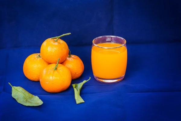 Glasses of orange juice and fruits with dried leaves