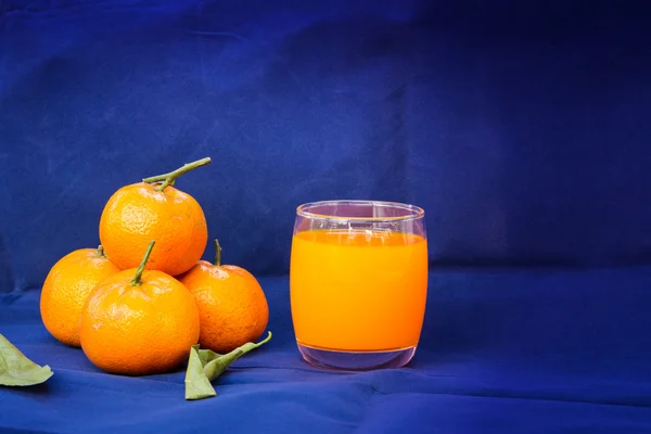 Glasses of orange juice and fruits with dried leaves