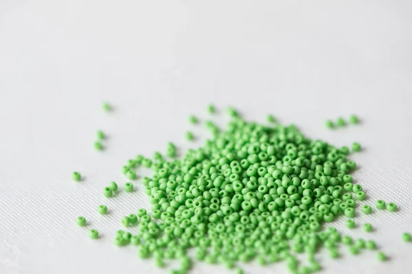 Scattered seed beads of light green color on a textile background