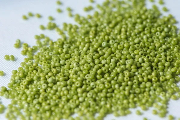 Scattered seed beads of olive color on the textile background