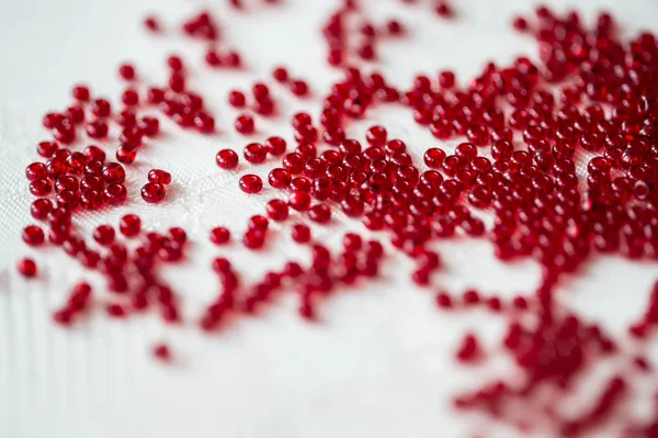 Seed beads of red color on the textile background close up