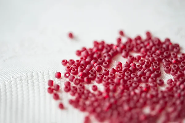 Seed beads of red color on the textile background close up