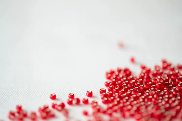 Seed beads of dark red color on the textile background close up