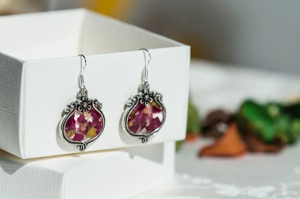 Earrings made of epoxy resin and natural rose petals close up