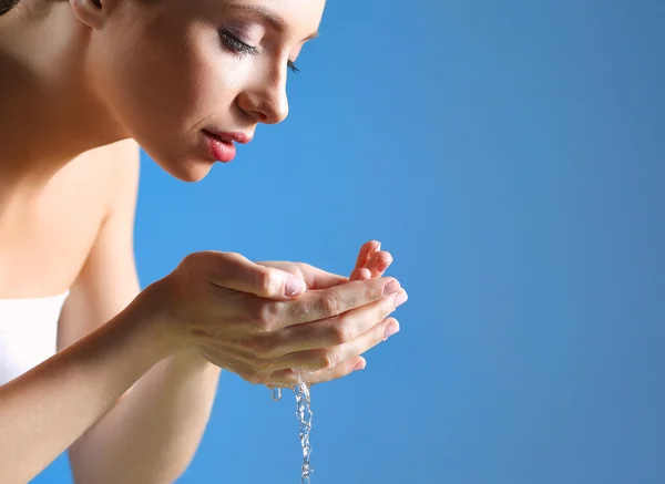 Young female washing her face with clear water