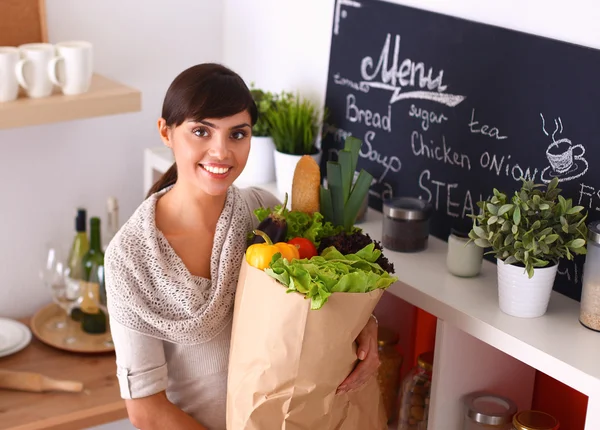 Young woman holding grocery shopping bag with vegetables Standing in the kitchen