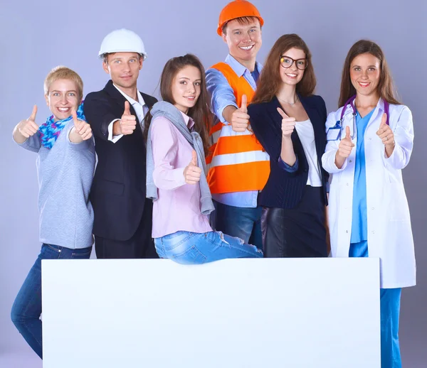 Portrait of smiling people with various occupations holding blank billboard showing ok