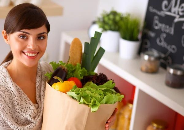 Young woman holding grocery shopping bag with vegetables Standing in the kitchen