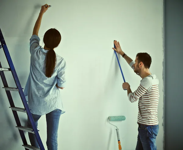 Portrait of happy smiling young couple  painting interior wall of new house