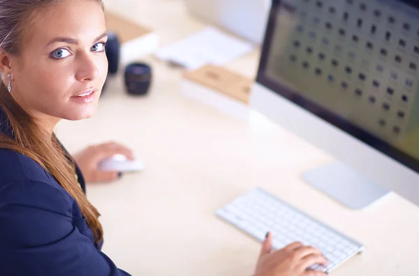 Young woman working in office, sitting at desk, using laptop