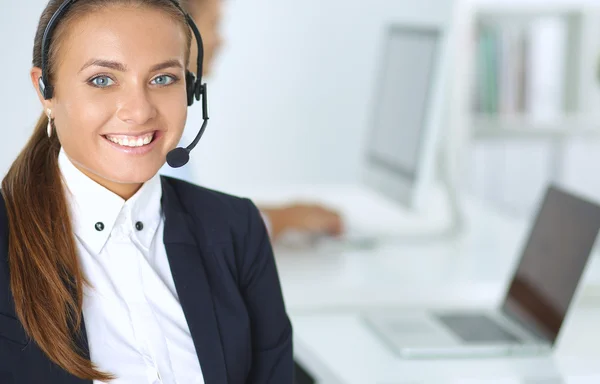 Portrait of a pretty call centre employee smiling at you while wearing her headset.
