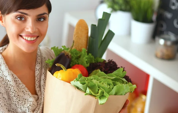 Young woman holding grocery shopping bag with vegetables Standing in the kitchen