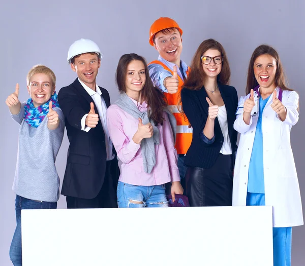 Portrait of smiling people with various occupations holding blank billboard showing ok