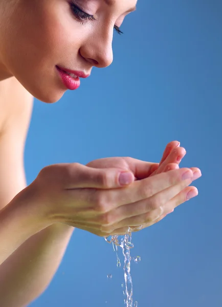 Young female washing her face with clear water