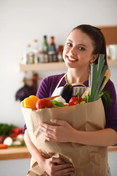 Young woman holding grocery shopping bag with vegetables Standing in the kitchen