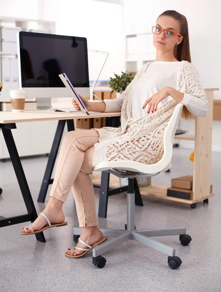 Young woman working in office, sitting at desk