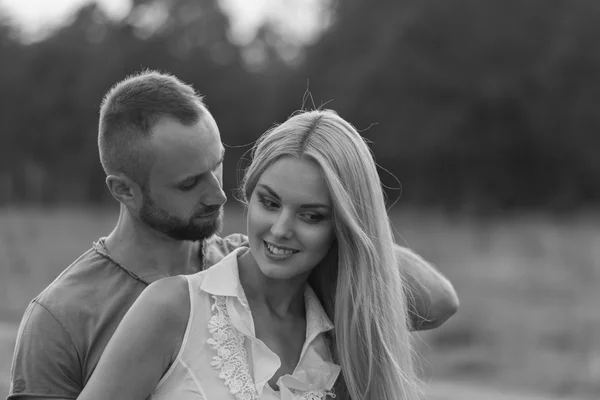 Black and white photo biker couple on a motorcycle in the field.