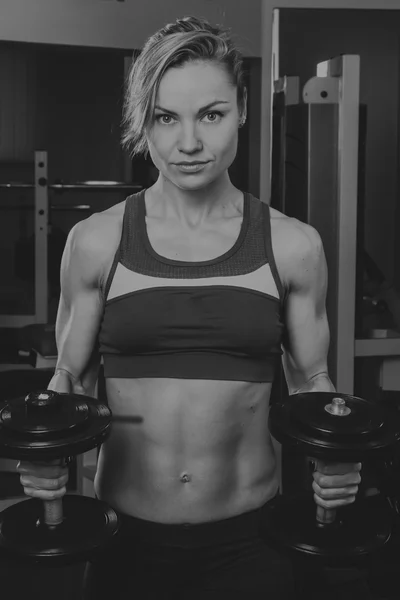 Sport blonde. Beautiful strong girl. Bodyfitness, women\'s fitness. Woman doing exercises at the gym. Beauty, health, and sports.Bodybuilder young adult sexy girl