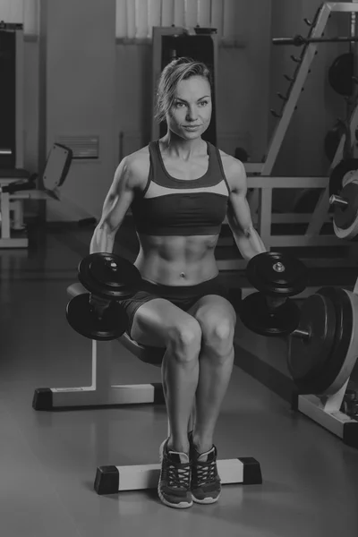 Sport blonde. Beautiful strong girl. Bodyfitness, women\'s fitness. Woman doing exercises at the gym. Beauty, health, and sports.Bodybuilder young adult sexy girl