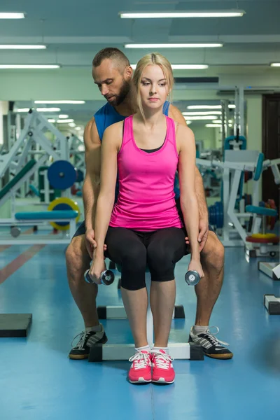 Young couple at a joint training session in the gym. Mutual assistance in carrying out exercises. Proper exercise. Photos for sporting and social magazines, posters and websites.