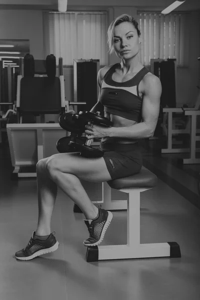 Sport blonde. Beautiful strong girl. Bodyfitness, women\'s fitness. Woman doing exercises at the gym. Beauty, health, and sports.Bodybuilder young adult sexy girl