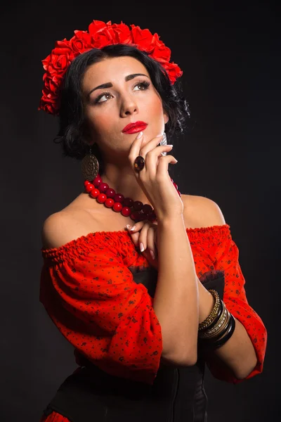 Beautiful, sexy woman in red. Beautiful image of the girl in red. Elegant wreath of red flowers, stylish jewelry, portrait of a girl.
