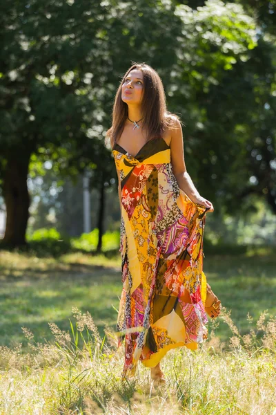 A young and attractive girl in beautiful summer dress middle of sunny meadows. Cheerful girl basking in the warm rays of the summer sun. Beautiful image of a carefree girl. Photos for magazines,