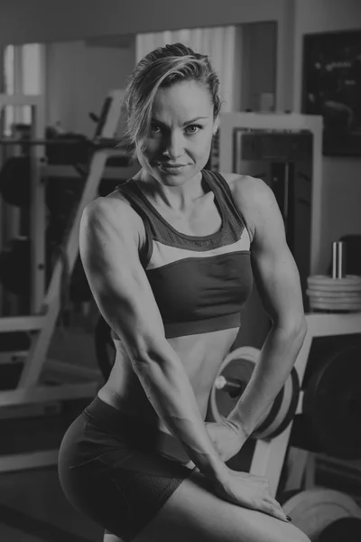 Sport blonde. Beautiful strong girl. Bodyfitness, women\'s fitness. Woman doing exercises at the gym. Beauty, health, and sports.Bodybuilder young adult sexy girl