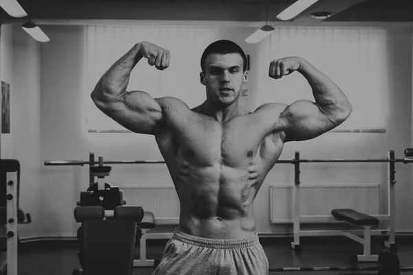 Bodybuilder makes exercise with dumbbells at the gym.