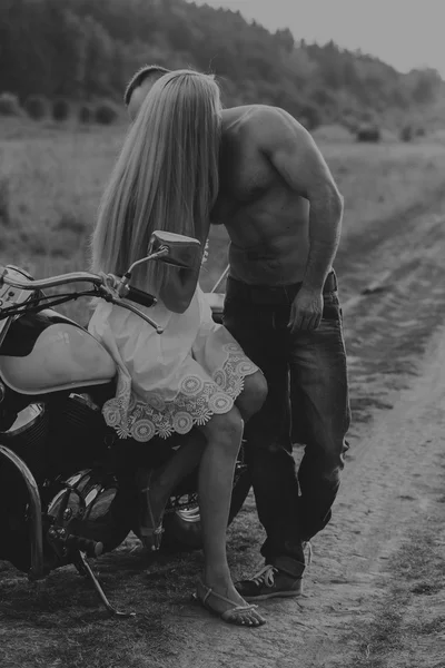 Black and white photo biker couple on a motorcycle in the field.