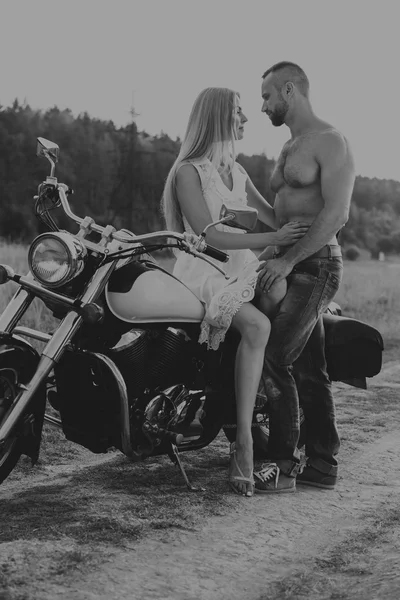 Black and white photo biker couple on a motorcycle in the field.