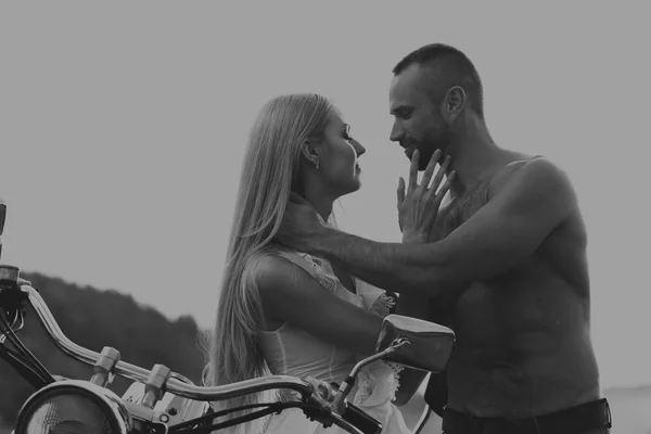 Black and white photo biker couple on a motorcycle in the field.