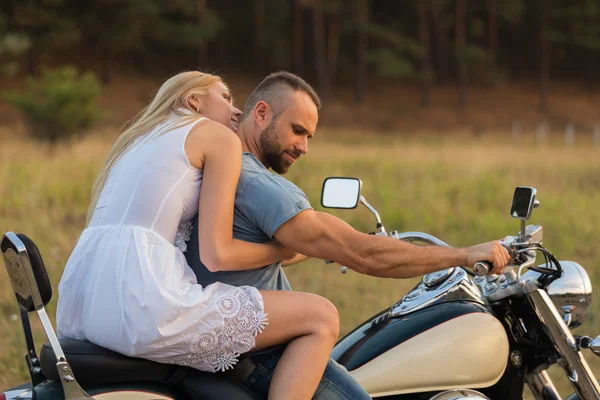 Newlyweds middle of the field on a motorcycle road. Happy couple traveling on a motorcycle.