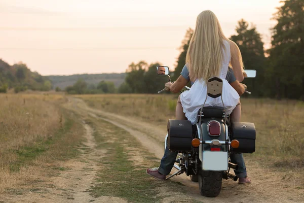 Newlyweds middle of the field on a motorcycle road. Happy couple traveling on a motorcycle.