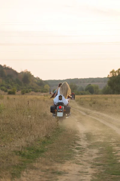 Newlyweds middle of the field on a motorcycle road. Happy couple traveling on a motorcycle.