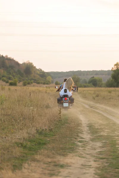 Newlyweds middle of the field on a motorcycle road. Happy couple traveling on a motorcycle.