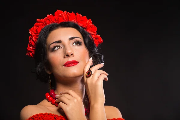 Beautiful, sexy woman in red. Beautiful image of the girl in red. Elegant wreath of red flowers, stylish jewelry, portrait of a girl.