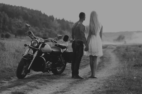 Black and white photo biker couple on a motorcycle in the field.